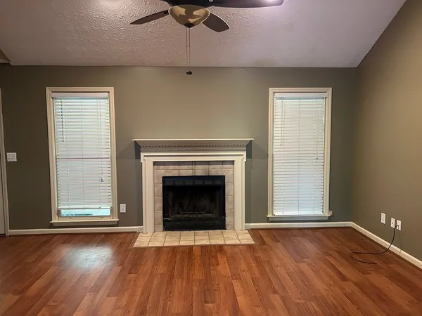 an empty room with wooden floor fireplace and windows