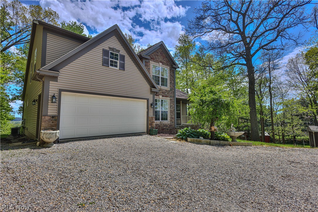 11154 Johnsford Road Southwest Beach City, OH 44608 - Photo 2 of 50 Exterior featuring stone and siding finishes, a two-car garage, and a gravel driveway