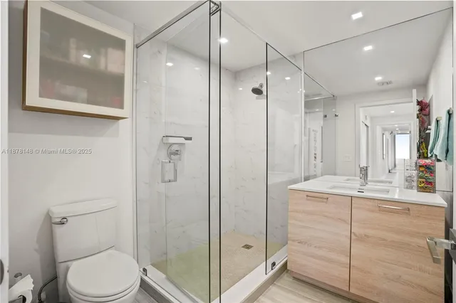 a bathroom with a granite countertop sink toilet a mirror a shower and vanity