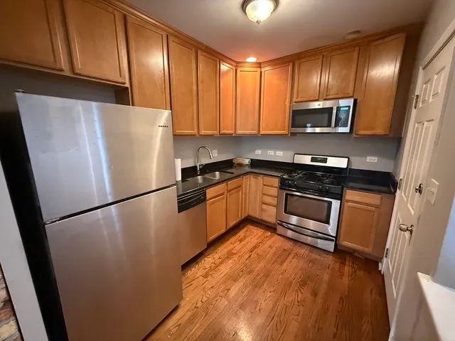 a kitchen with stainless steel appliances granite countertop a refrigerator a stove a sink dishwasher and a microwave