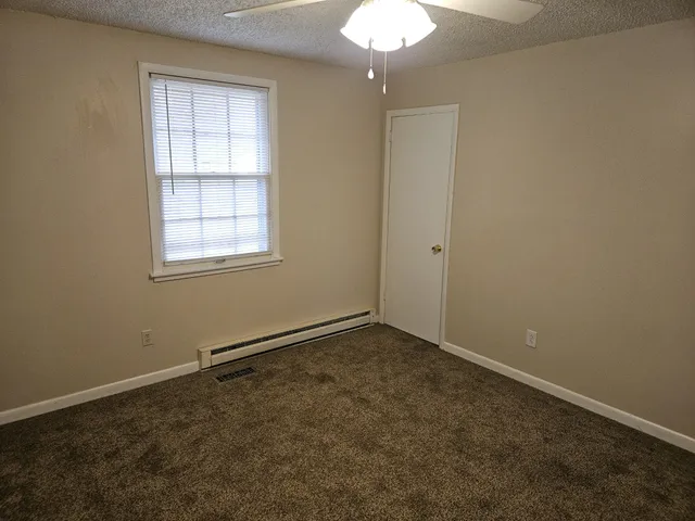 an empty room with a chandelier fan and windows