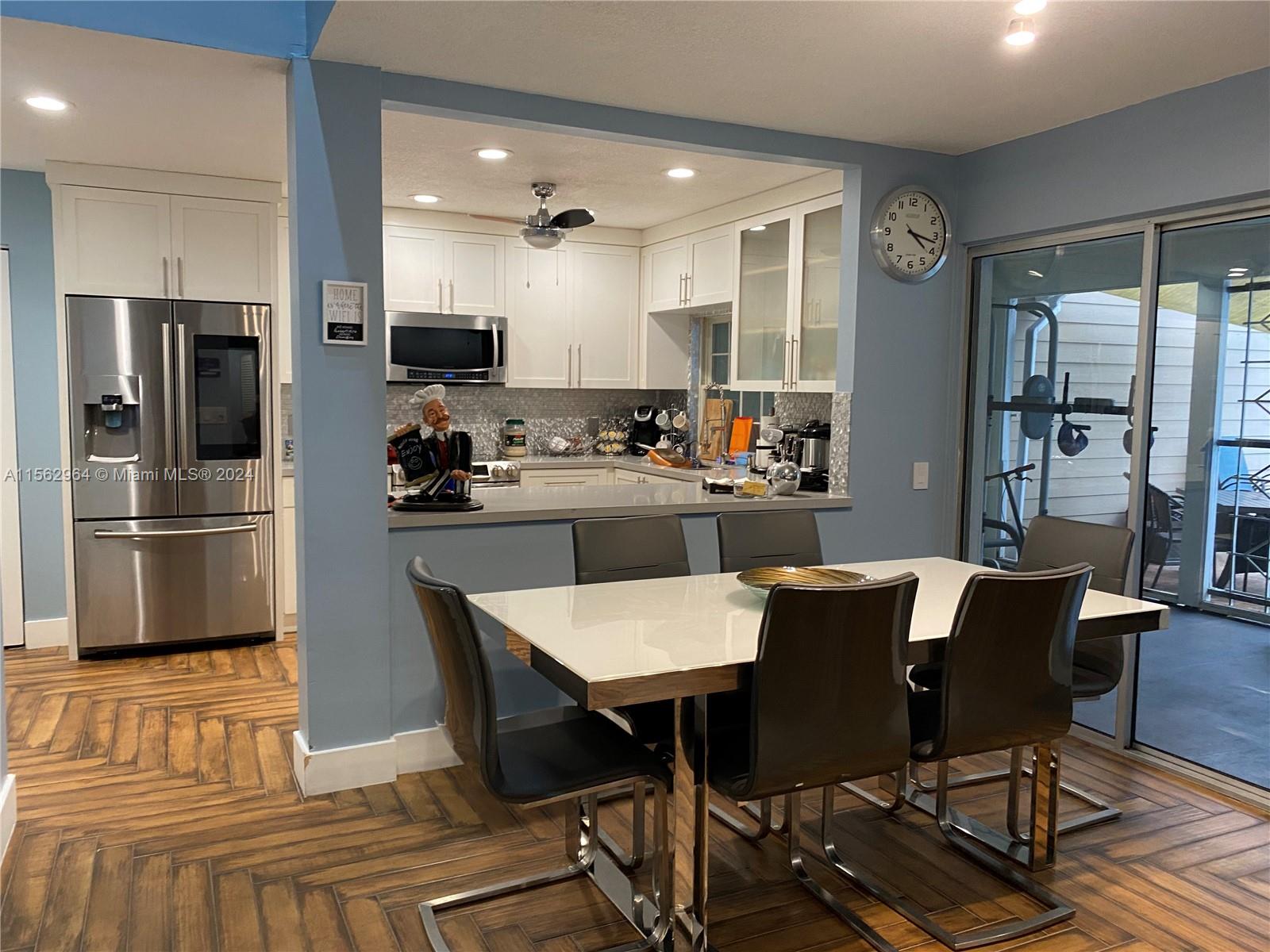 14530 Southwest 142nd Pl Circle Miami, FL 33186 - Photo 7 of 28 a kitchen with stainless steel appliances a dining table chairs refrigerator and sink