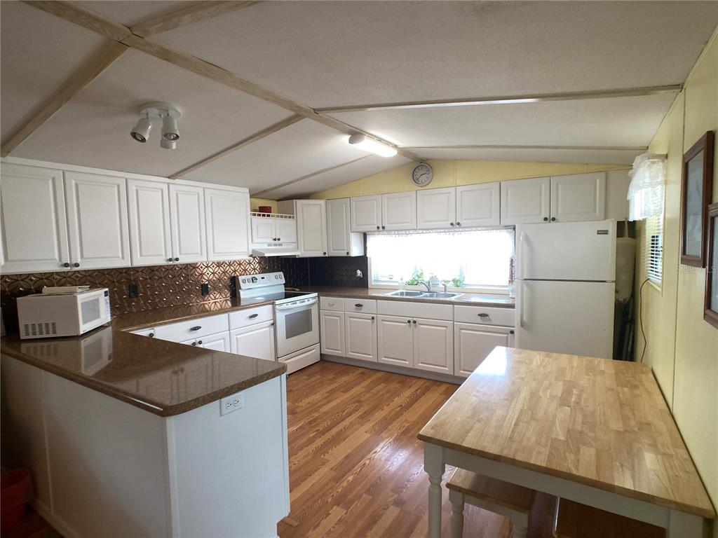 1710 7th Street Southwest, Unit 24 Ruskin, FL 33570 - Photo 5 of 44 a kitchen with granite countertop a refrigerator a sink dishwasher a stove top oven a kitchen island and cabinets with wooden floor