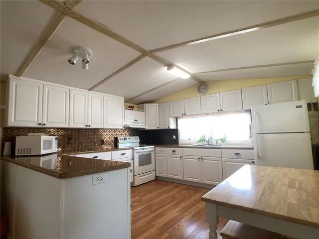 a kitchen with a sink a stove a refrigerator and white cabinets