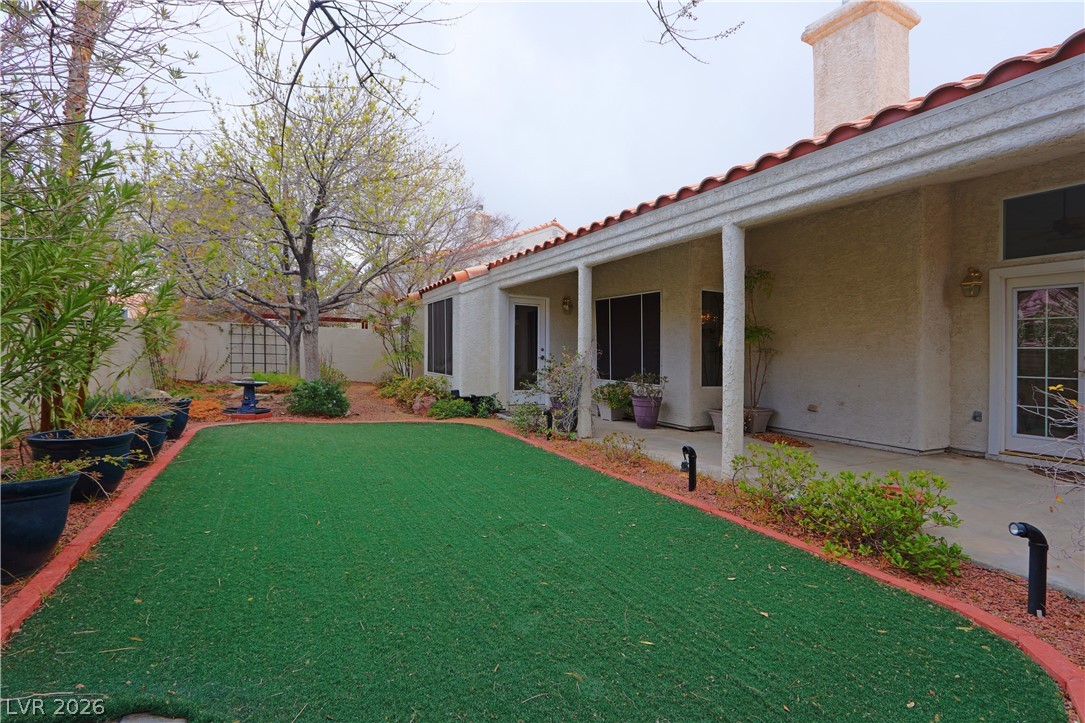 2108 Crestpoint Way Las Vegas, NV 89134 - Photo 25 of 27 A terracotta-tiled patio extends to a neatly manicured turf lawn, framed by verdant plantings.