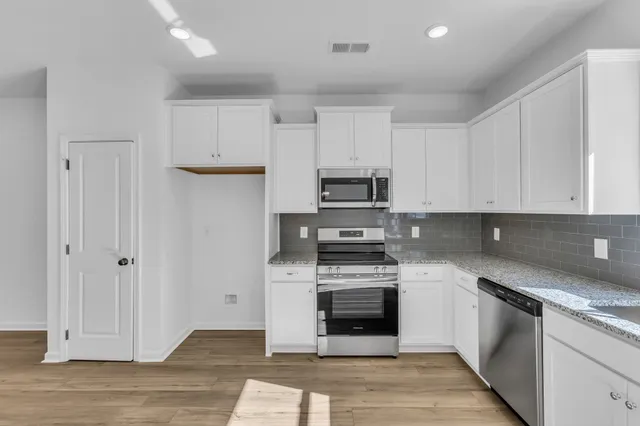 a kitchen with stainless steel appliances granite countertop a sink a stove cabinets and a window