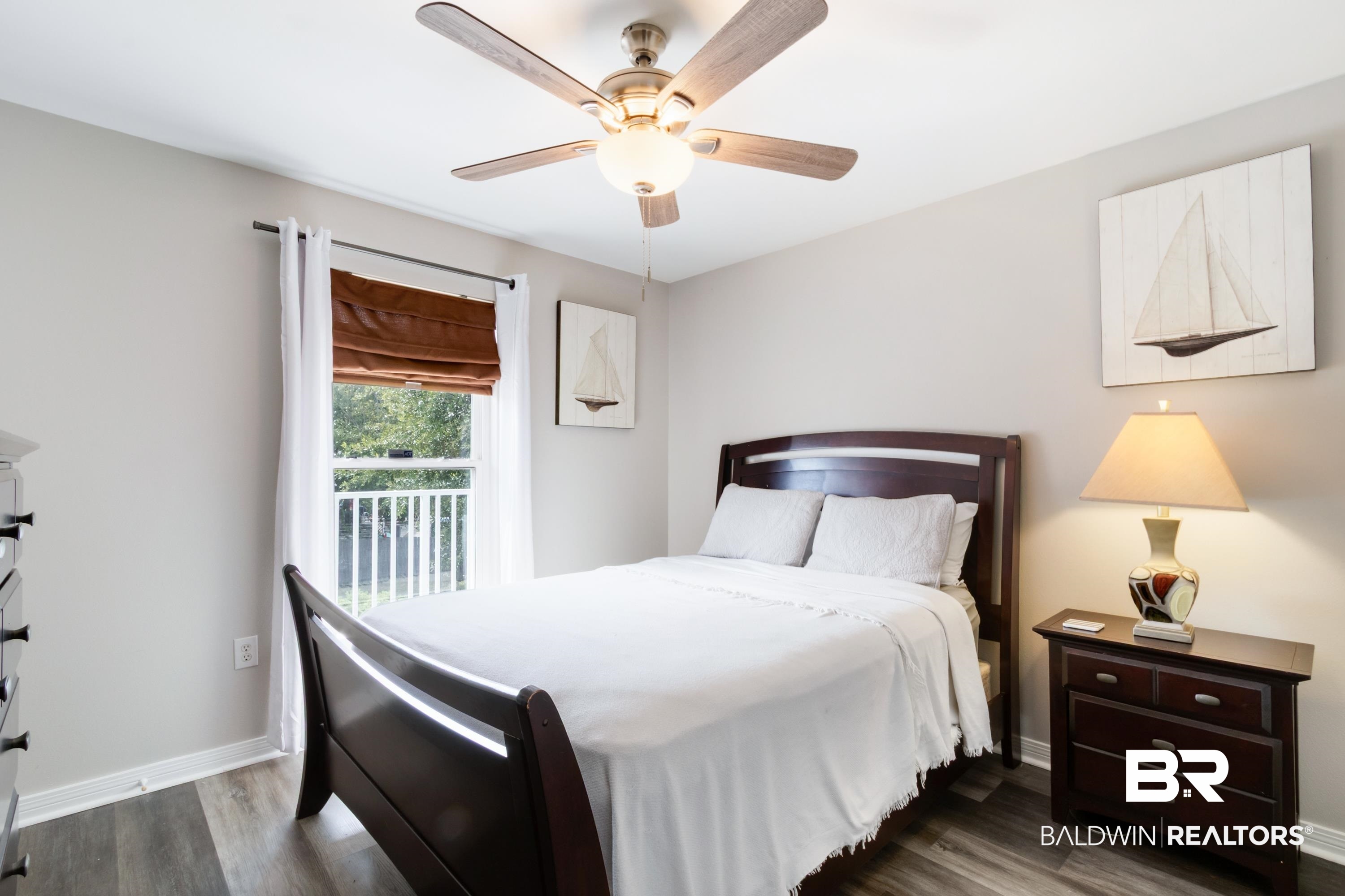 25957 Canal Road, Unit 208 Orange Beach, AL 36561 - Photo 14 of 28 Bedroom featuring a ceiling fan with integrated lighting, wood-finish flooring, a window with a brown roman shade, and neutral-toned walls