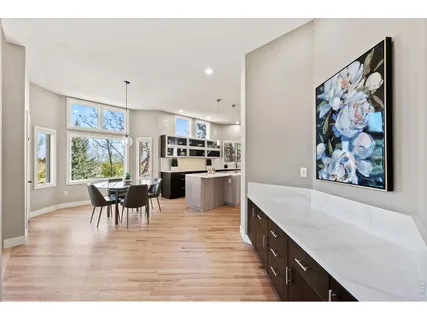 a large white kitchen with stainless steel appliances kitchen island granite countertop a dining table chairs and a refrigerator
