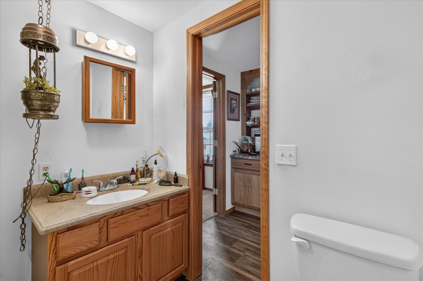 26115 4157th Road Nowata, OK 74048 - Photo 20 of 36 Wood-finish vanity with a built-in sink, framed mirror, and overhead vanity lighting