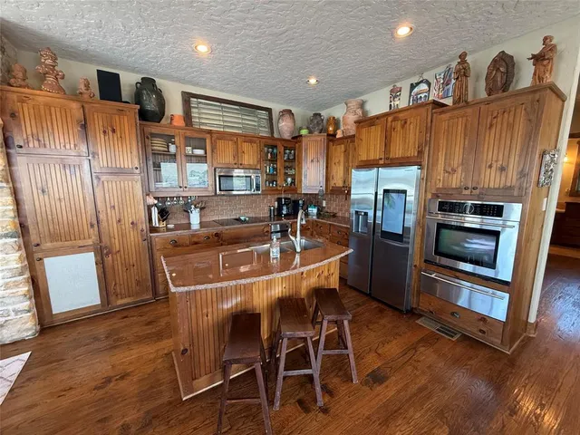 a kitchen with stainless steel appliances a refrigerator a stove a microwave oven a sink with island and chairs