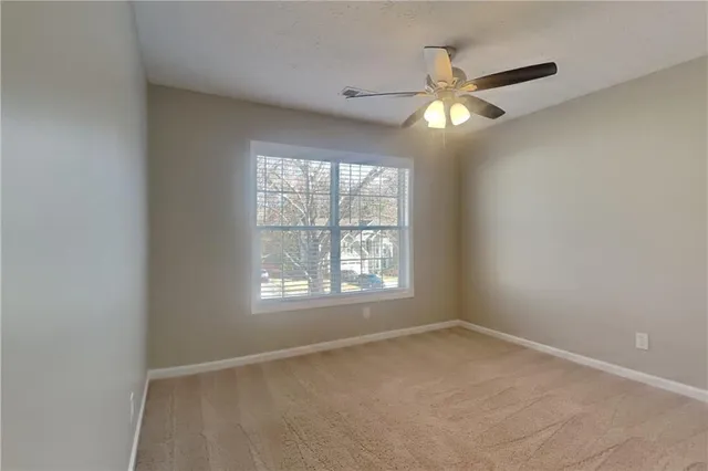 an empty room with a window and a fan