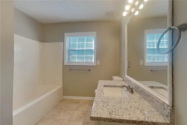 a bathroom with a granite countertop sink a toilet and bathtub