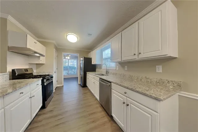 a large kitchen with cabinets wooden floor and stainless steel appliances