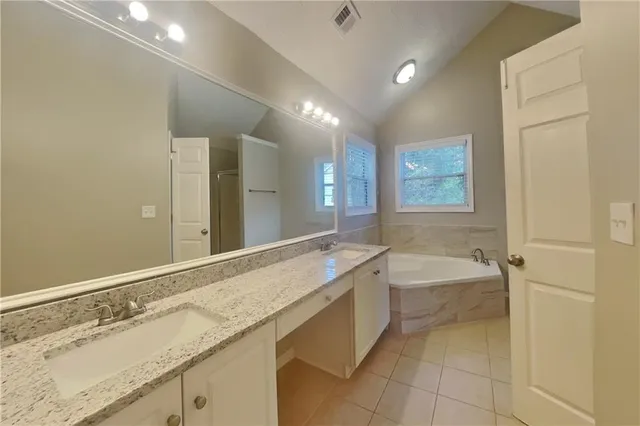 a bathroom with a granite countertop sink a bathtub and mirror