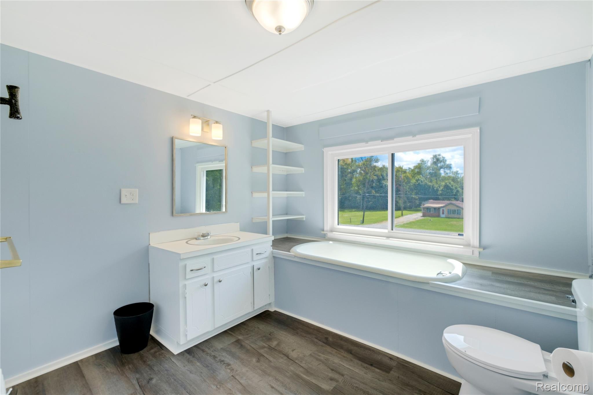3363 East Pierson Road Flint, MI 48506 - Photo 16 of 27 Bathroom featuring a built-in tub, white vanity with integrated sink, wood-finish flooring, and built-in shelving