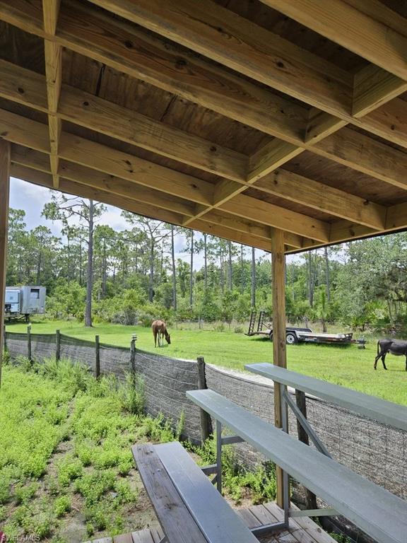 1375 Ash Road Northwest LaBelle, FL 33935 - Photo 9 of 26 Exposed wood beam ceiling structure with a wood-planked overhead, overlooking a fenced grassy expanse