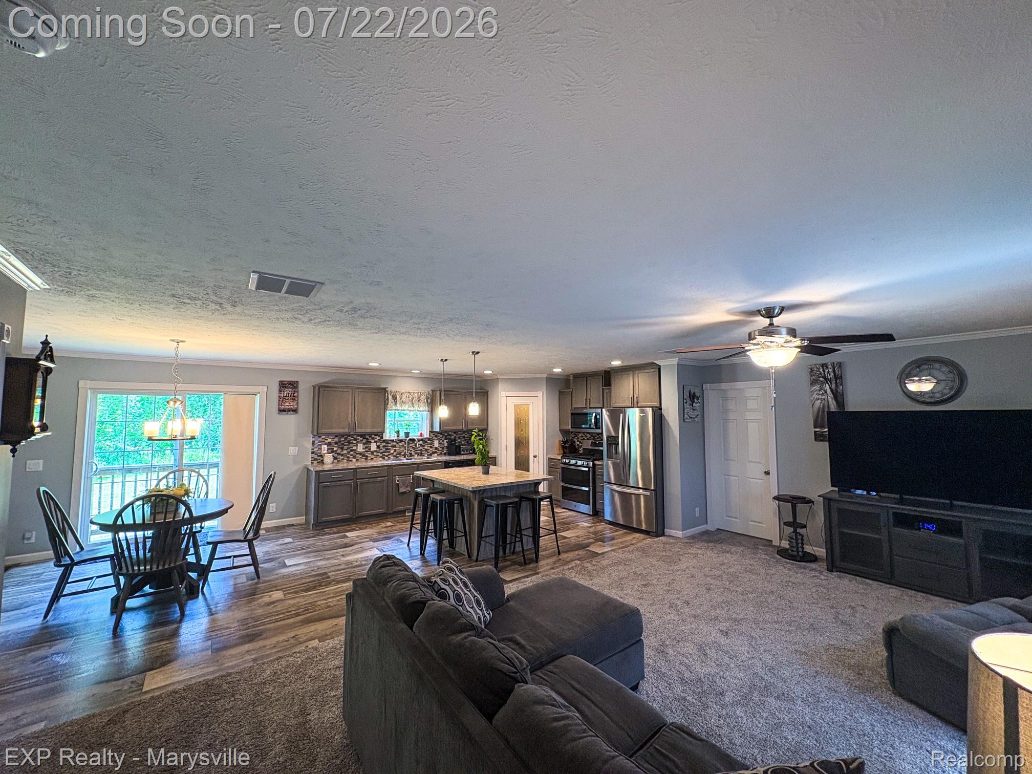 2601 Beach Road Port Huron, MI 48060 - Photo 8 of 34 Open-concept living area featuring wood-finish flooring, a kitchen island with pendant lighting, stainless steel appliances, and a sliding glass door to an exterior deck