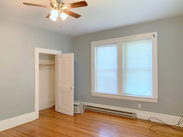 a view of empty room with wooden floor and fan