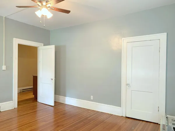an empty room with wooden floor and ceiling fan