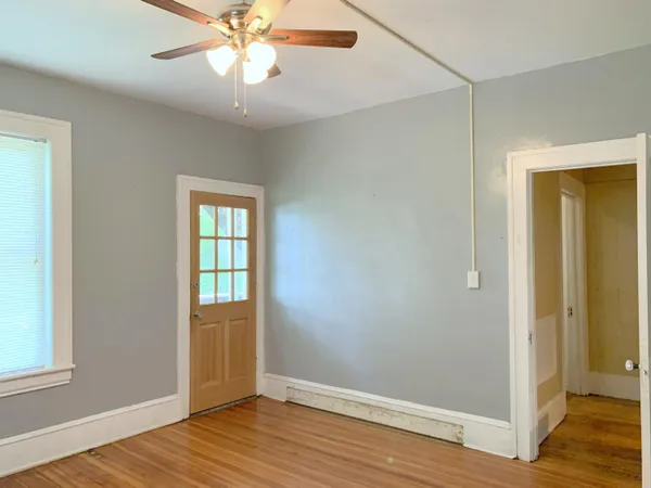 a view of an empty room with wooden floor and a window