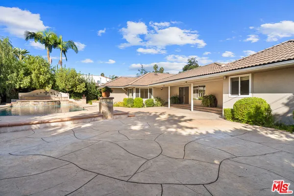 a view of a white house with a big yard and potted plants