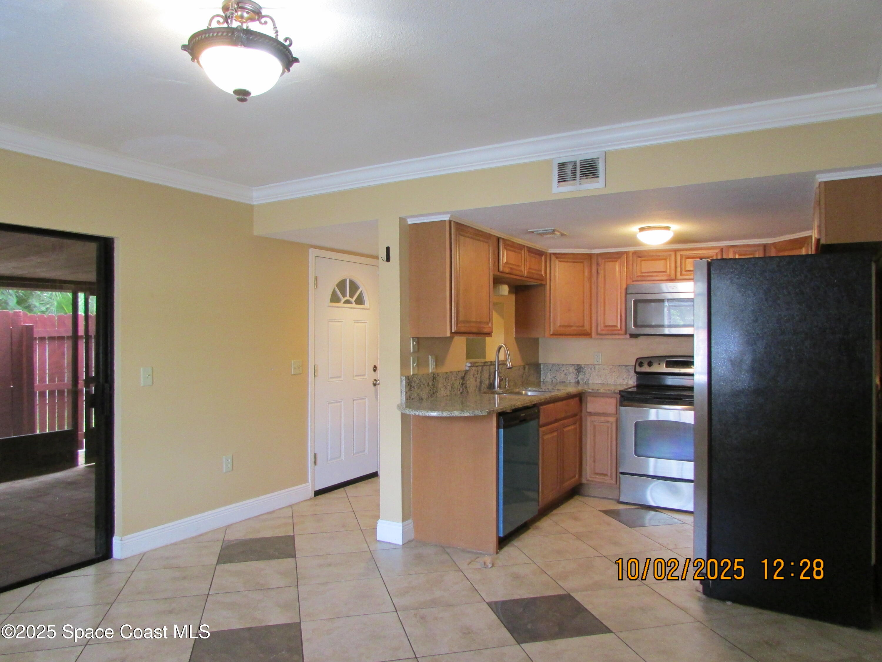 49 Piney Branch Way, Unit A Melbourne, FL 32904 - Photo 4 of 25 a kitchen with stainless steel appliances granite countertop a refrigerator and a stove top oven