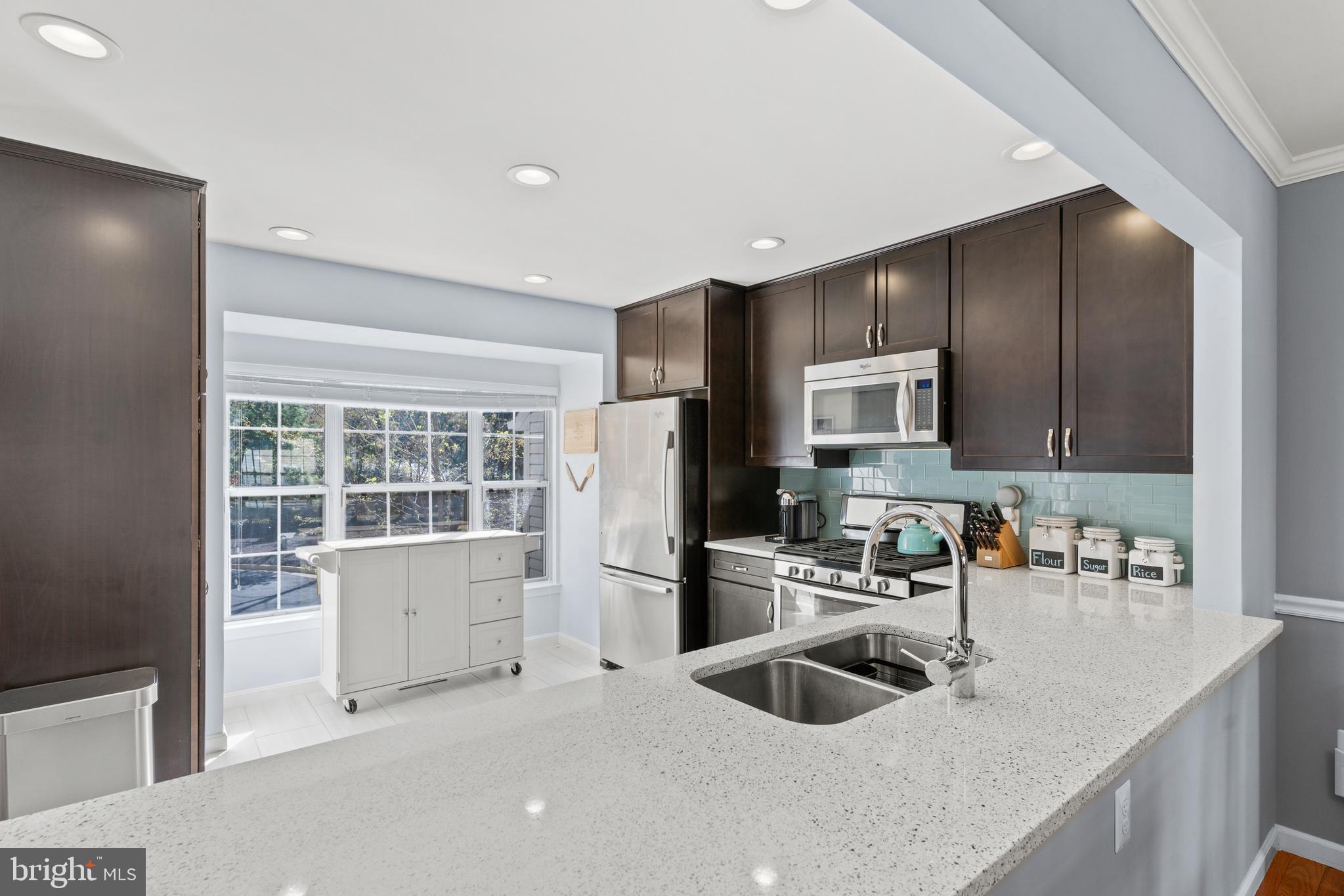 a kitchen that has a sink cabinets counter space stainless steel appliances and a window