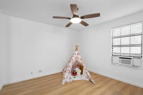 a view of a room with wooden floor fan and windows