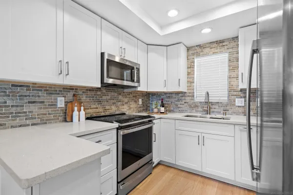 a kitchen with stainless steel appliances granite countertop white cabinets a sink a stove a refrigerator and white cabinets