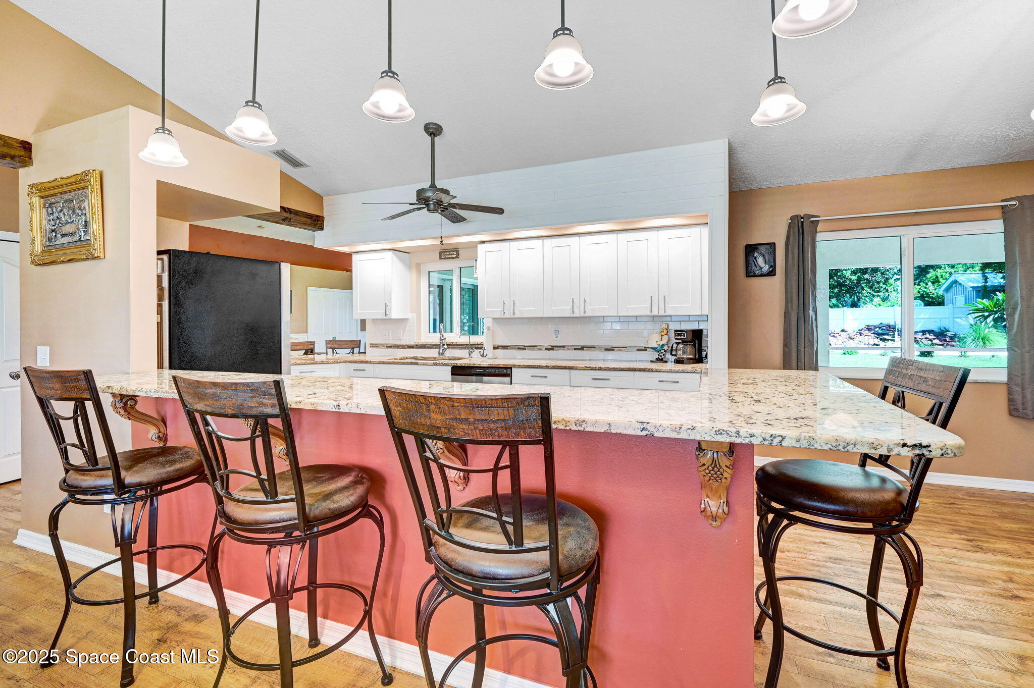 1507 Meadowbrook Road Northeast Palm Bay, FL 32905 - Photo 8 of 50 a kitchen with stainless steel appliances kitchen island granite countertop a dining table chairs and white cabinets
