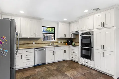a kitchen with granite countertop white cabinets and stainless steel appliances