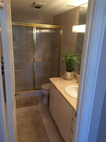 a bathroom with a granite countertop sink a toilet and shower