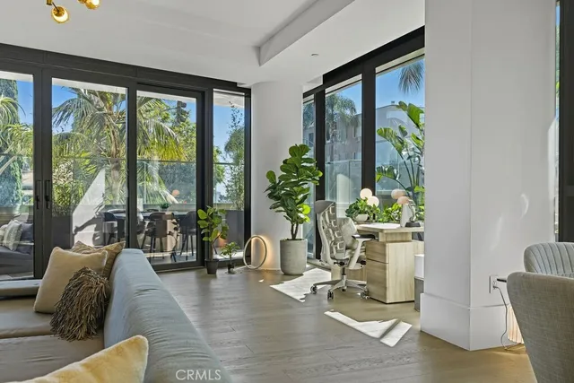 a living room with furniture large windows and wooden floor