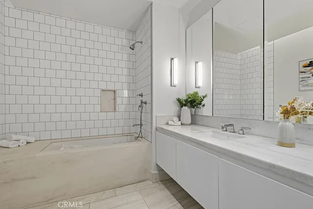 a bathroom with a double vanity sink mirror and bathtub