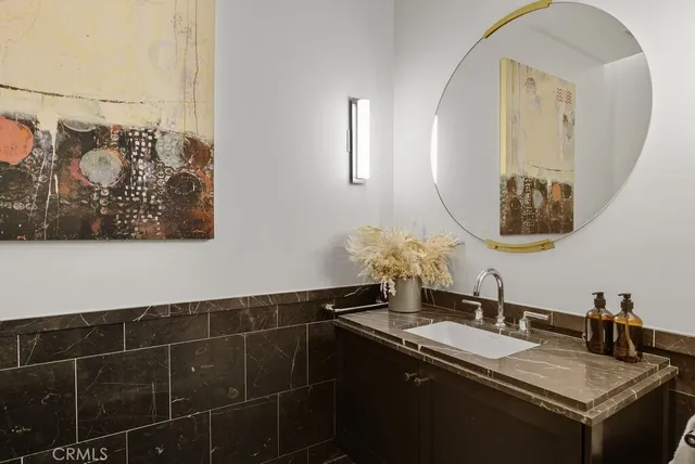 a room with granite countertop a sink and a mirror