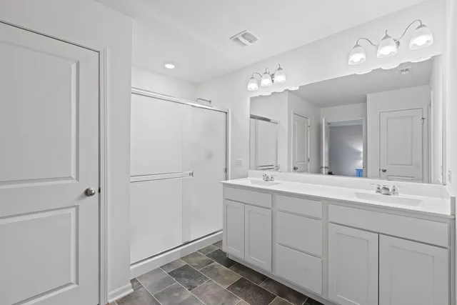 a bathroom with a double vanity sink mirror and shower
