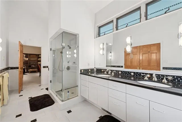 a bathroom with a double vanity sink a mirror and shower