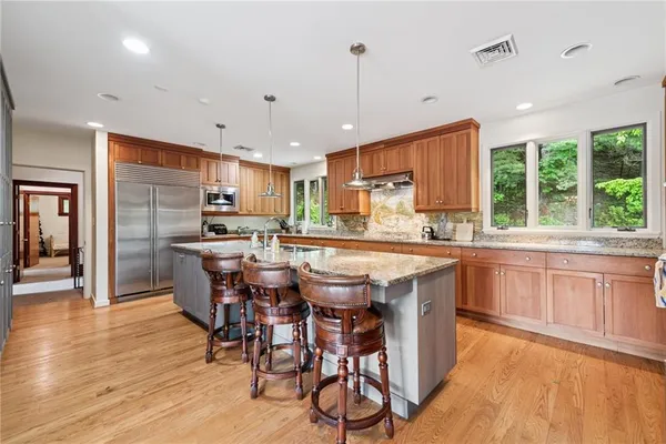 a kitchen with stainless steel appliances granite countertop a kitchen island hardwood floor sink stove dining table and chairs