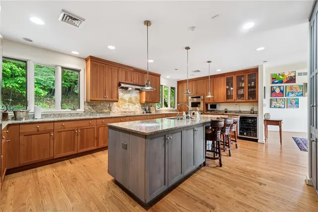 a kitchen with stainless steel appliances granite countertop wooden cabinets a stove top oven a sink and dishwasher a oven with wooden floor