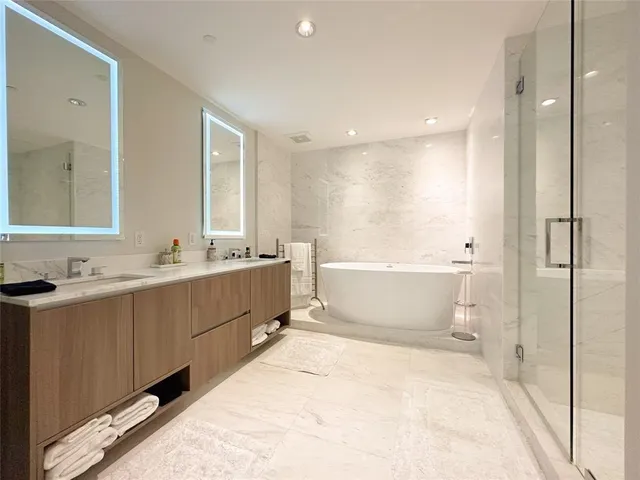 a bathroom with a double vanity sink a mirror and a bathtub