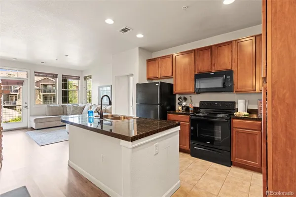 a kitchen with kitchen island granite countertop a stove sink and refrigerator