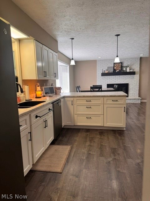 2760 Haines Road Madison, OH 44057 - Photo 14 of 33 Open-concept kitchen featuring an island with pendant lighting, white cabinetry with dark hardware, stone-finish countertops, wood-finish flooring, and a whitewashed brick fireplace