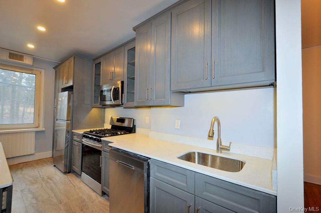 69 Harney Road, Unit 3A Scarsdale, NY 10583 - Photo 9 of 22 Renovated Kitchen with center Island, pendent lighting, Granite Counters, Stainless Steel Appliance including a dishwasher, range, microwave and refrigerator. The wall separating the eat-in-kitchen and living room have been removed and a center Island installed with electric and USB outlets installed to create an open concept.