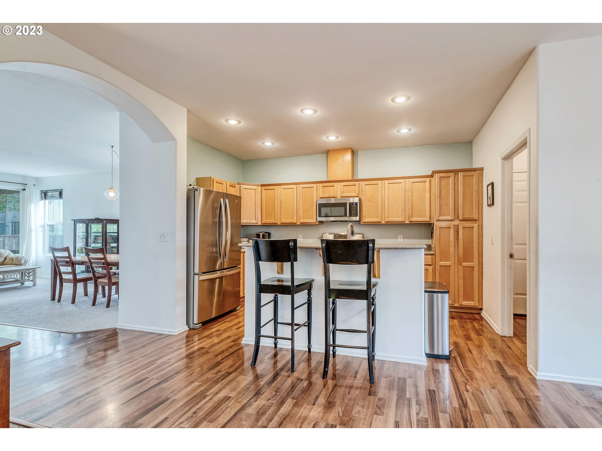 5588 Wales Drive Eugene, OR 97402 - Photo 15 of 41 a open kitchen with stainless steel appliances kitchen island granite countertop a refrigerator a stove a dining table and chairs with wooden floor