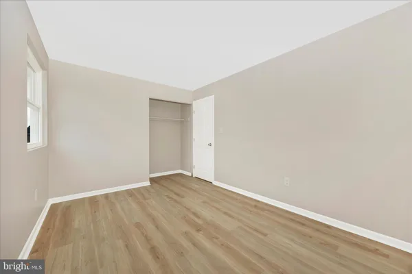 a view of an empty room with wooden floor and windows
