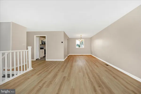 an empty room with wooden floor chandelier and windows