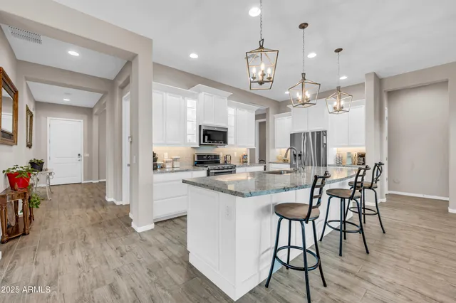 a kitchen with stainless steel appliances kitchen island granite countertop a table chairs and a refrigerator