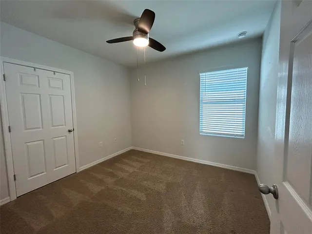 an empty room with a ceiling fan and window