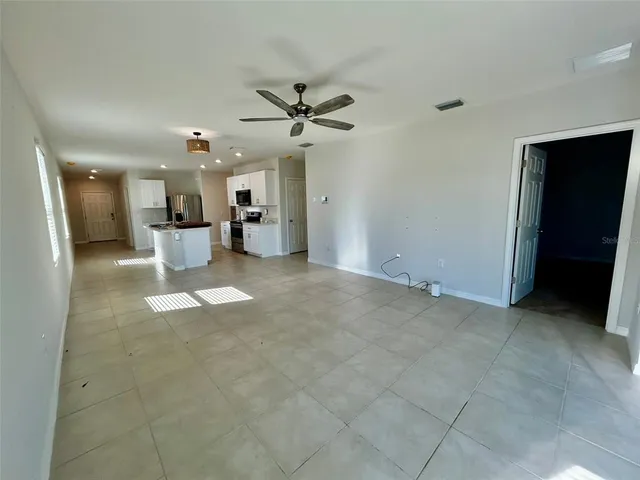 a view of a livingroom with a chandelier fan and windows