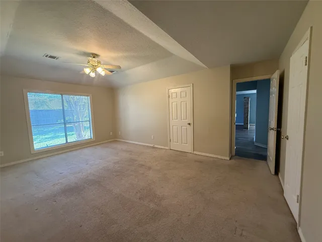 an empty room with a chandelier fan and windows